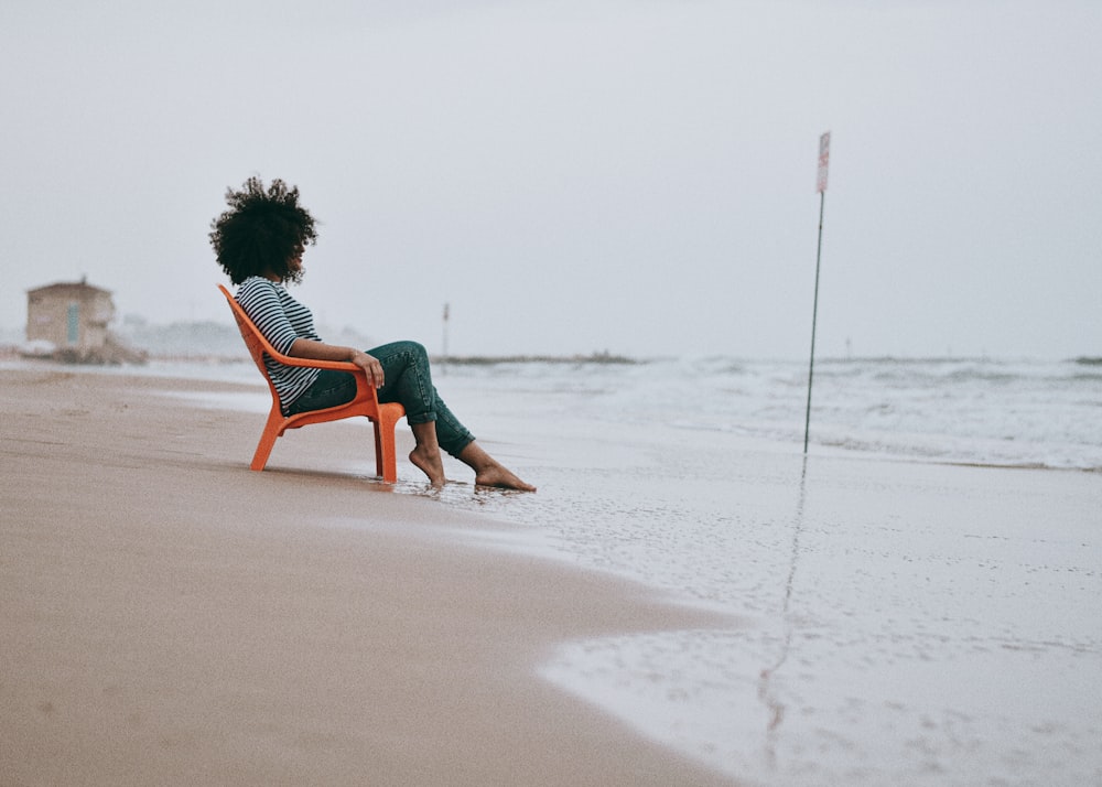 woman in green dress sitting on brown wooden chair on beach during daytime