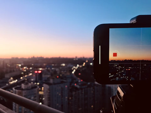 Close-up of a camera lens capturing a vibrant cityscape at dusk.