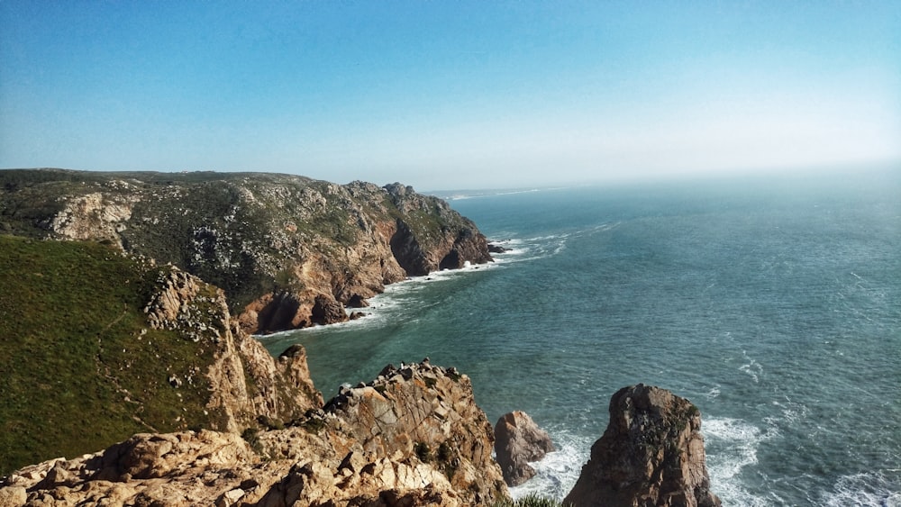 brown rock formation near blue sea under blue sky during daytime