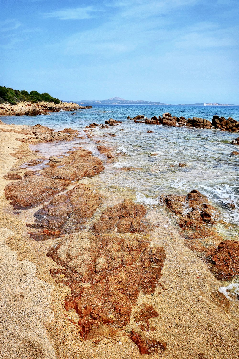 brown rocky shore near green mountain under blue sky during daytime