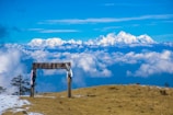 brown wooden bench on brown field under blue and white cloudy sky during daytime