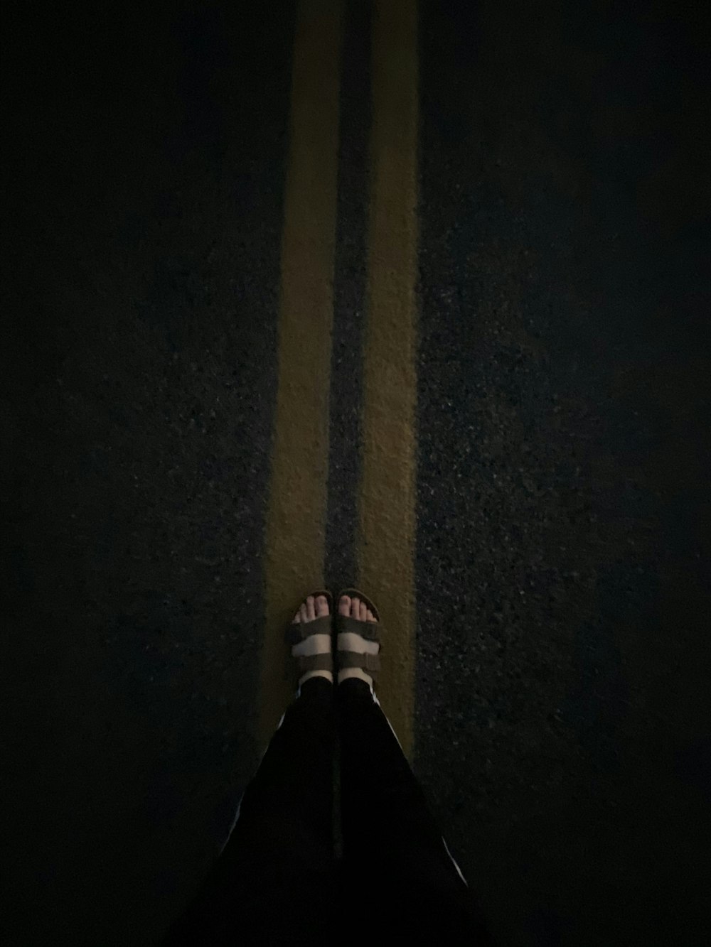person in black pants standing on black asphalt road