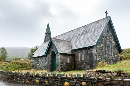 gray concrete church surrounded by green grass field in Killarney National Park Ireland