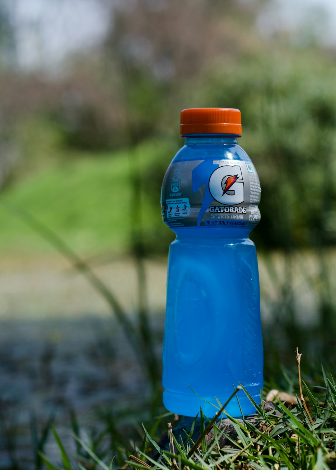 blue gatorade plastic bottle on green grass