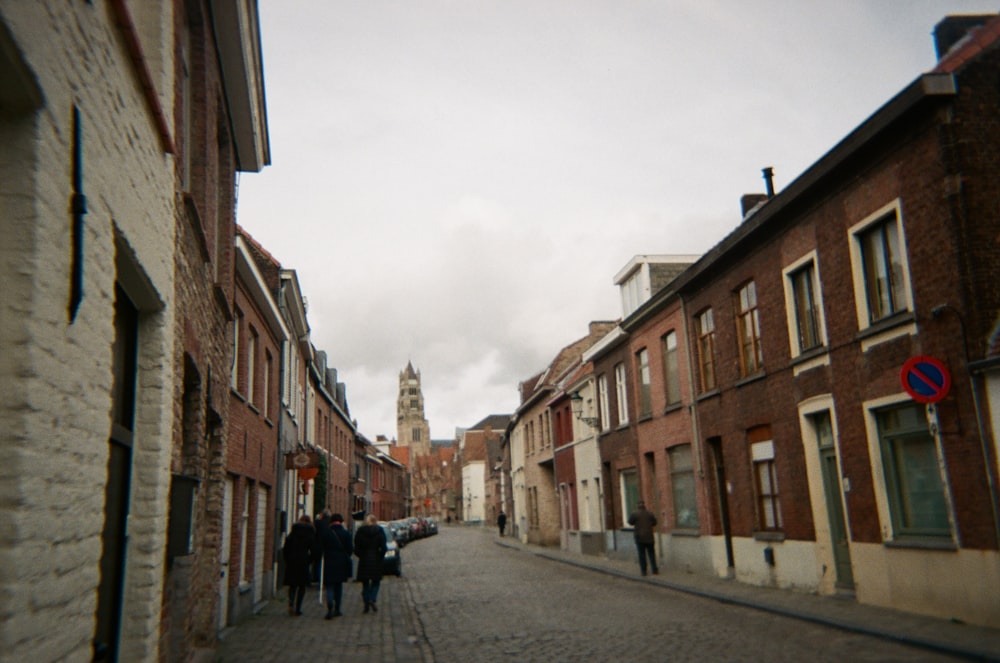 a group of people walking down a street next to tall buildings