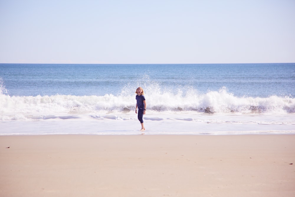 낮 동안 해변을 걷고 있는 검은 드레스를 입은 여자