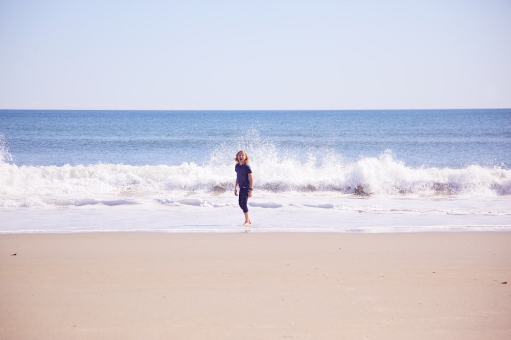 donna in vestito nero che cammina sulla spiaggia durante il giorno