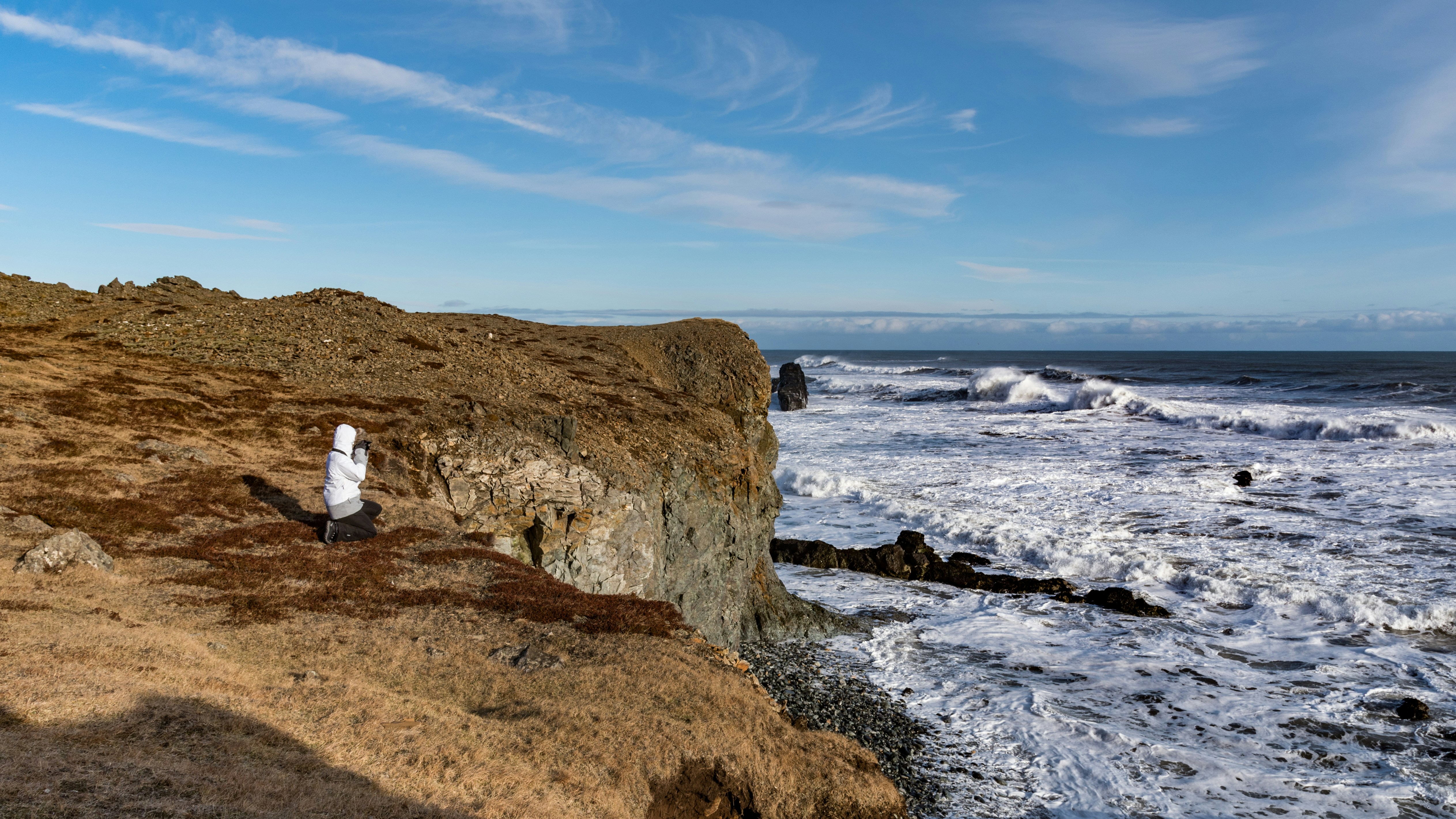 man and woman sitting on brown rock formation near sea during daytime