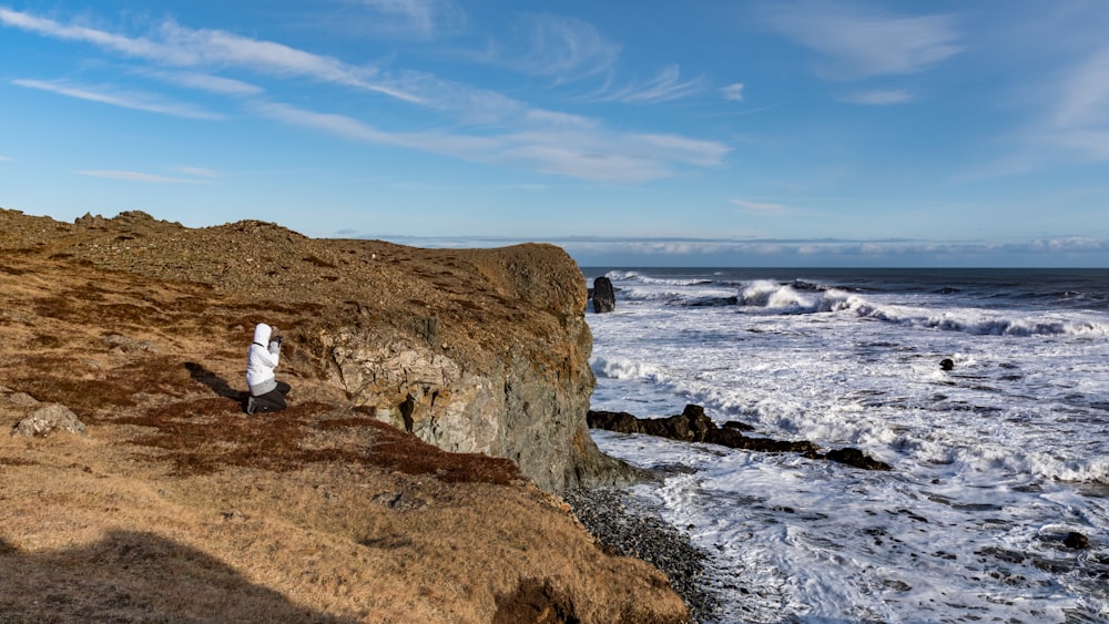 man and woman sitting on brown rock formation near sea during daytime