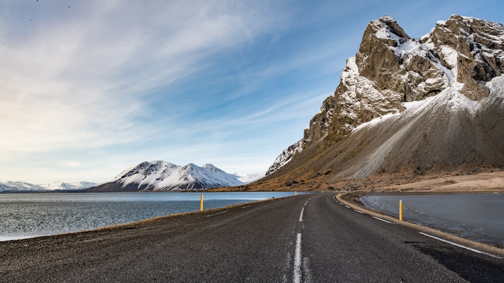 gray concrete road near snow covered mountain during daytime