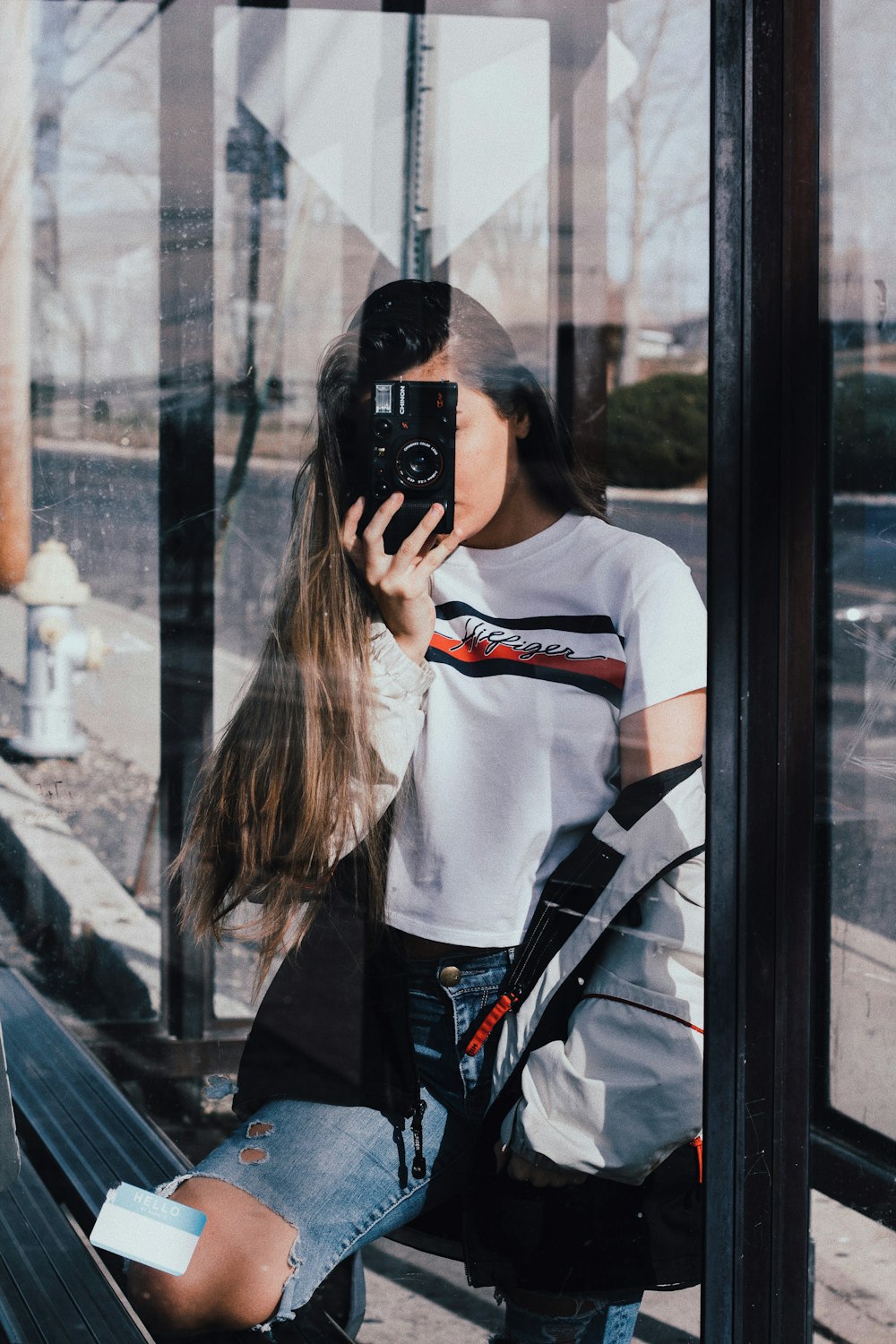 woman in white and black adidas shirt holding black smartphone