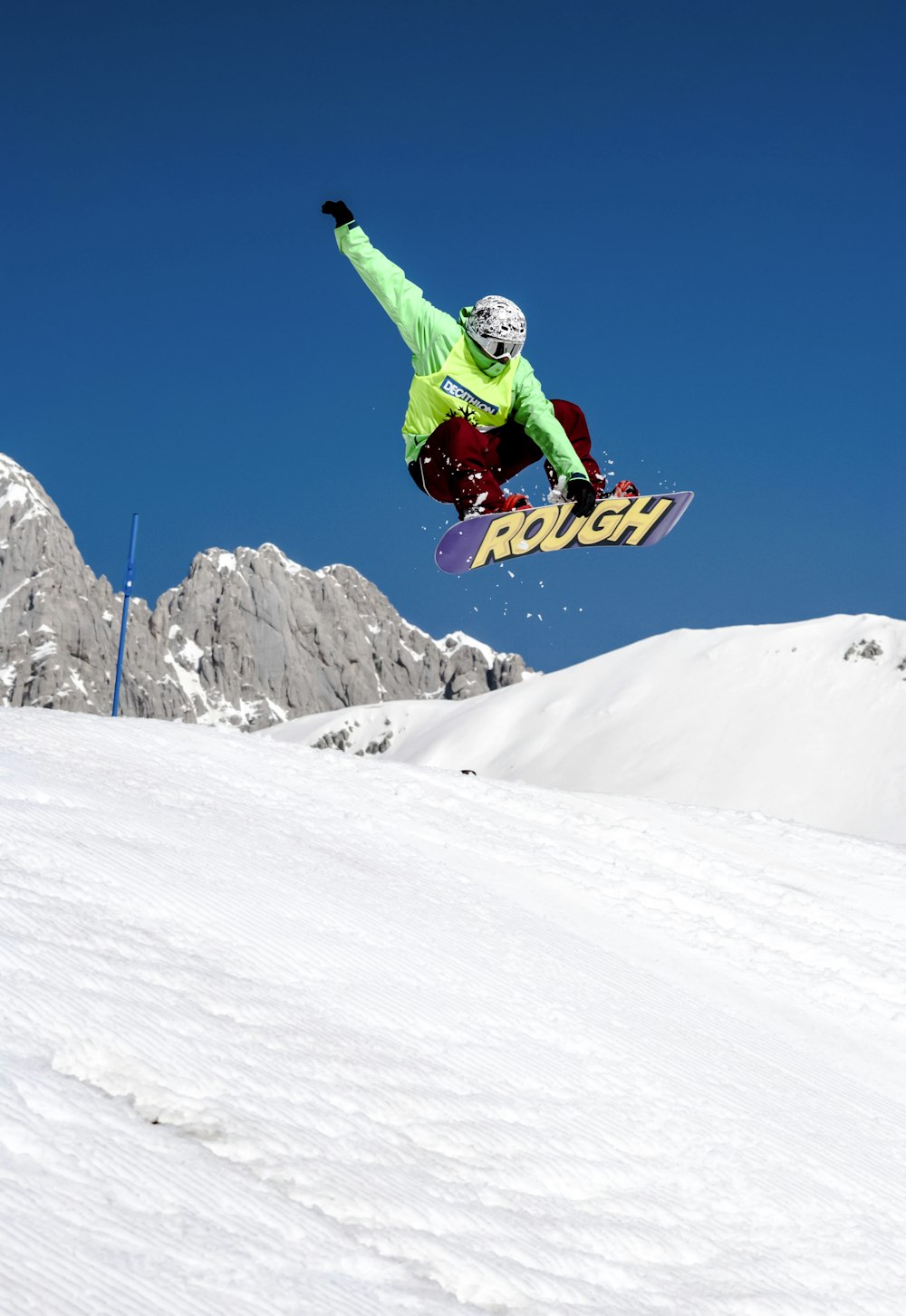 Mann in grüner Jacke fährt tagsüber Snowboard auf schneebedeckten Bergen