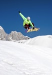 man in green jacket riding snowboard on snow covered mountain during daytime