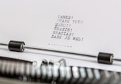 A close-up of a typewriter with a sheet of paper in it. The paper contains the word 'thank you' typed in multiple languages, including German, English, French, Italian, Spanish, and Dutch.
