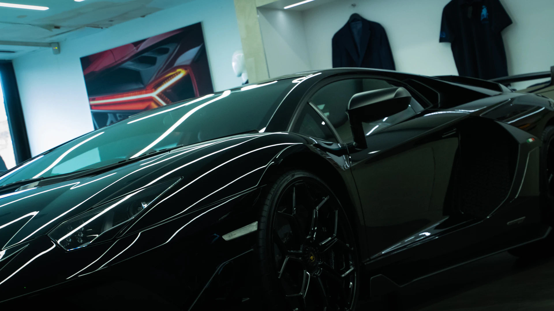 A sleek black luxury sports car gleaming under soft golden lighting, parked in a modern showroom with dark, elegant interiors.