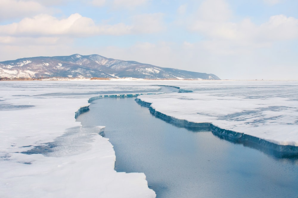 snow covered mountain near body of water during daytime