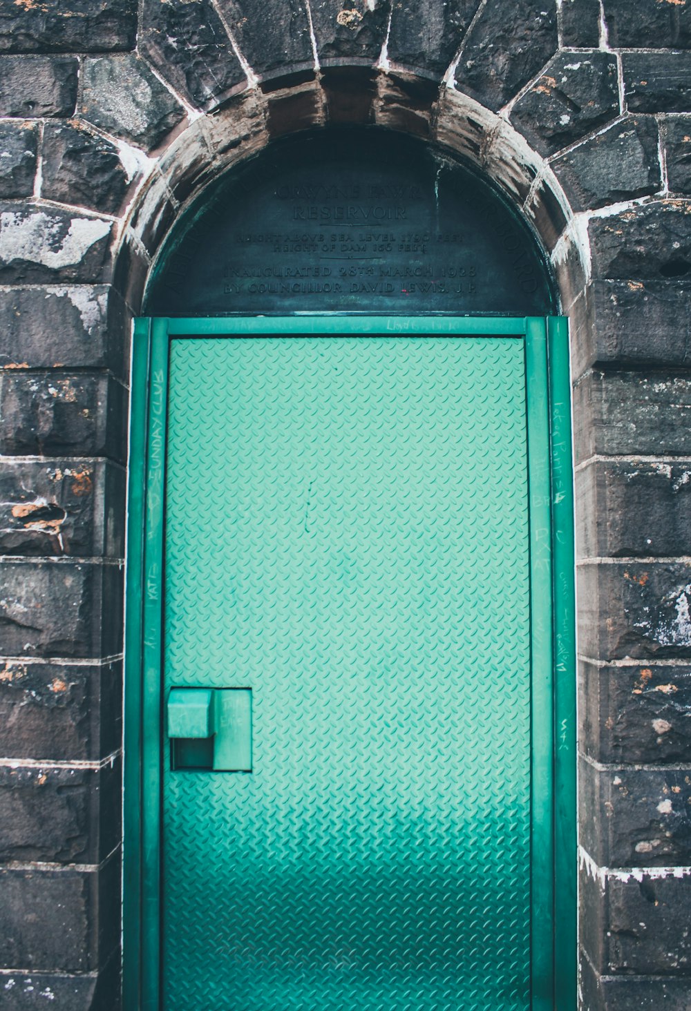 green wooden door on brick wall