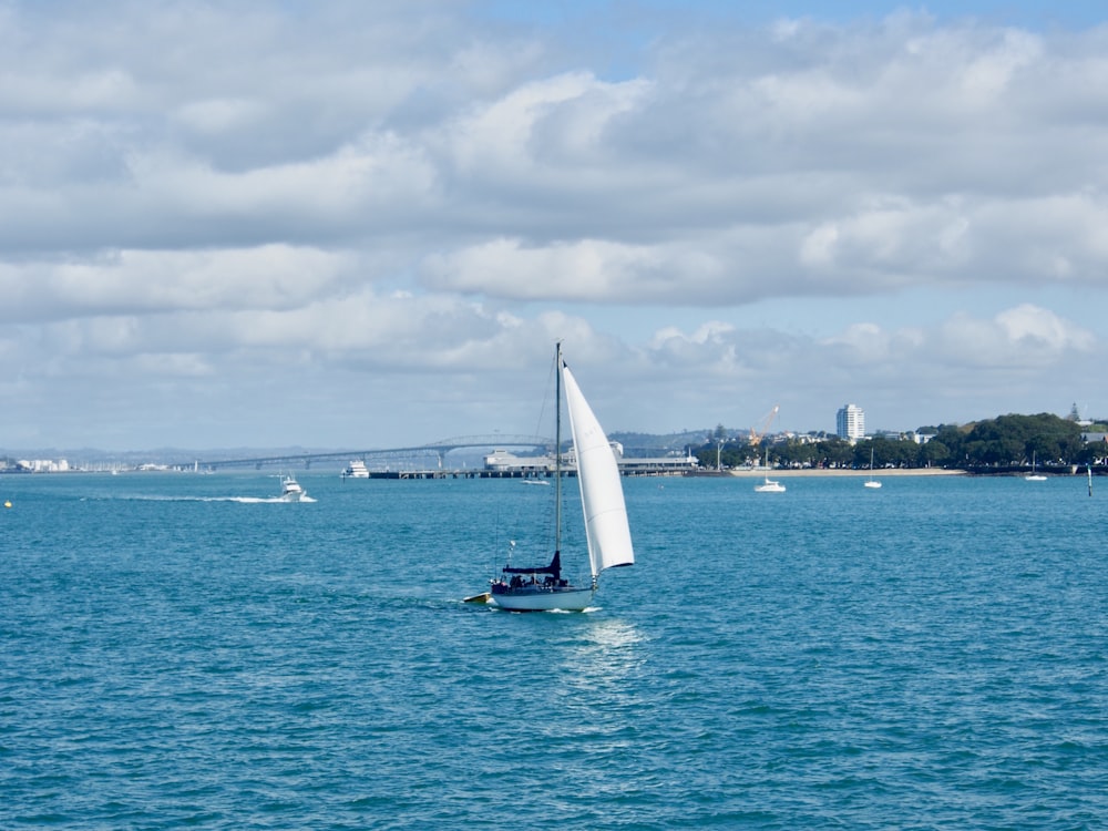 white sailboat on sea under white clouds during daytime