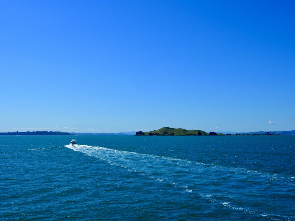 green island on blue sea under blue sky during daytime