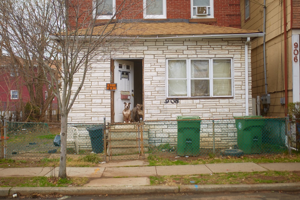 brown and white brick house with blue metal fence