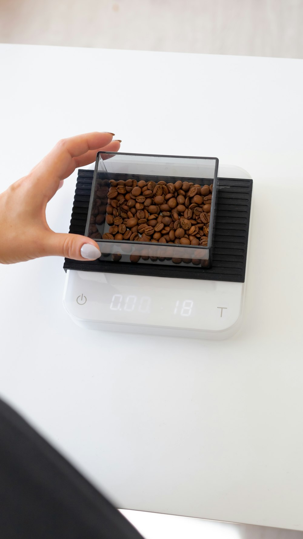 person holding white and black box with brown beans