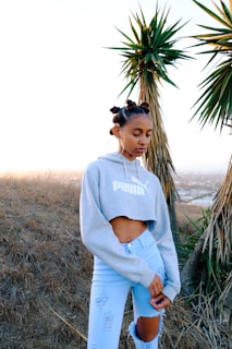 woman in gray crew neck t-shirt standing near green palm tree during daytime