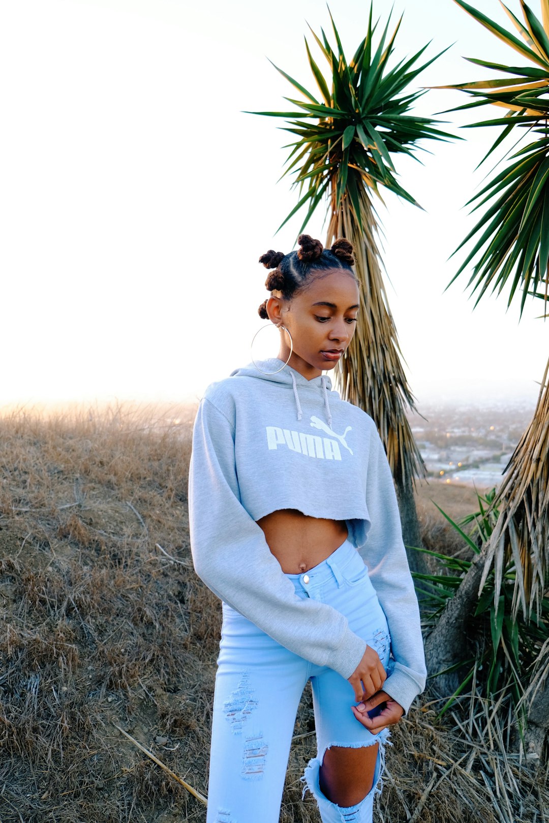 woman in gray crew neck t-shirt standing near green palm tree during daytime