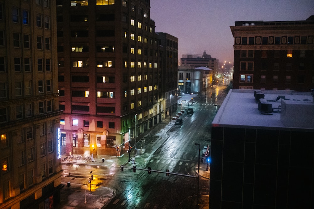 cars on road in between high rise buildings during night time