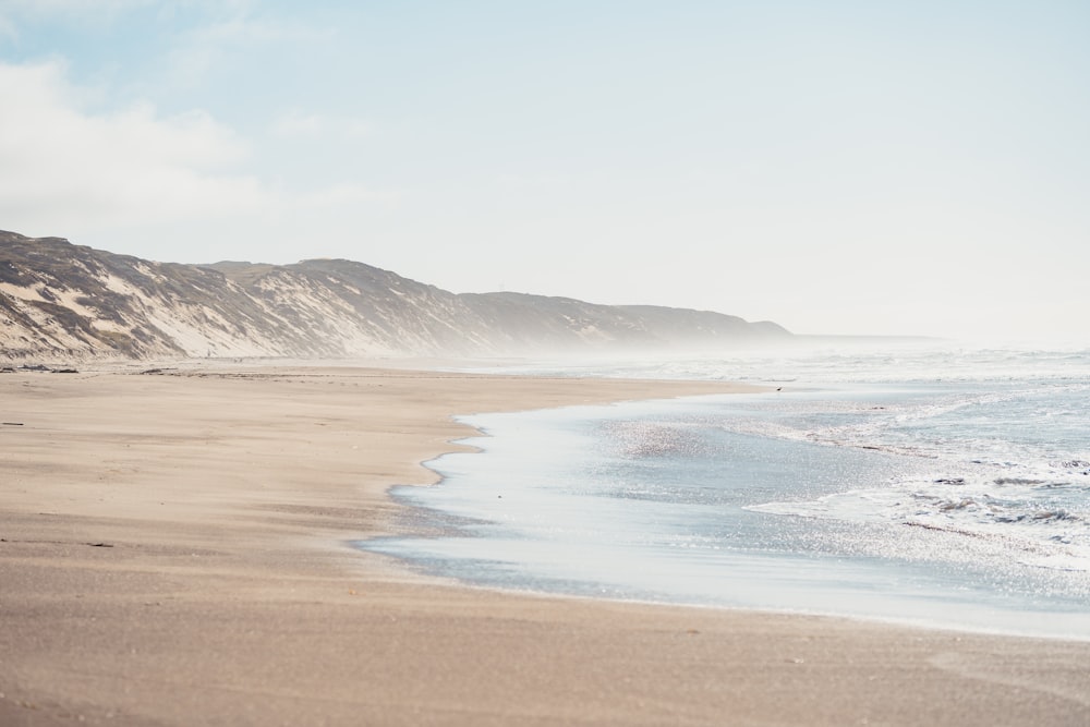 brown sand beach with mountain in distance