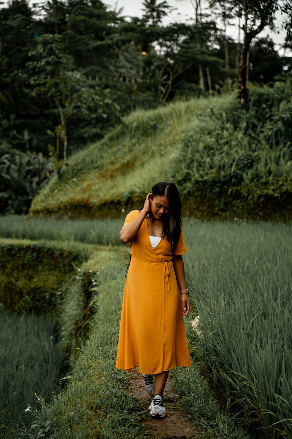 woman in orange dress standing on green grass field during daytime