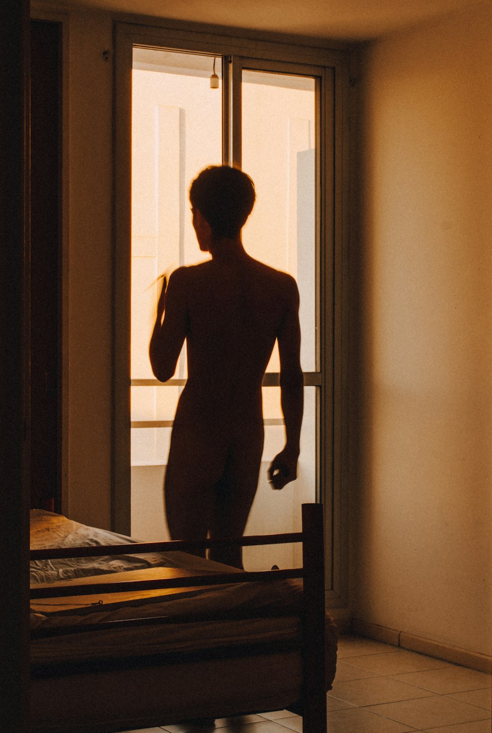 man in black tank top standing in front of window