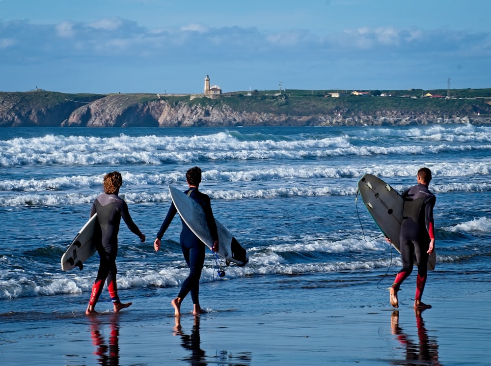 낮 동안 해변에서 서핑 보드를 들고 걷는 남자와 여자