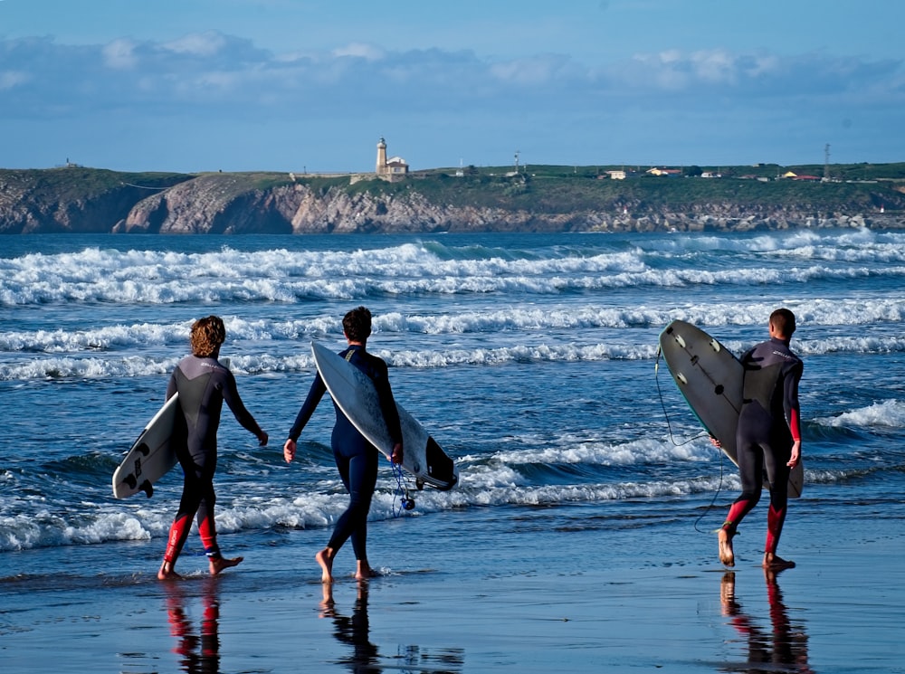 homme et femme tenant une planche de surf marchant sur la plage pendant la journée