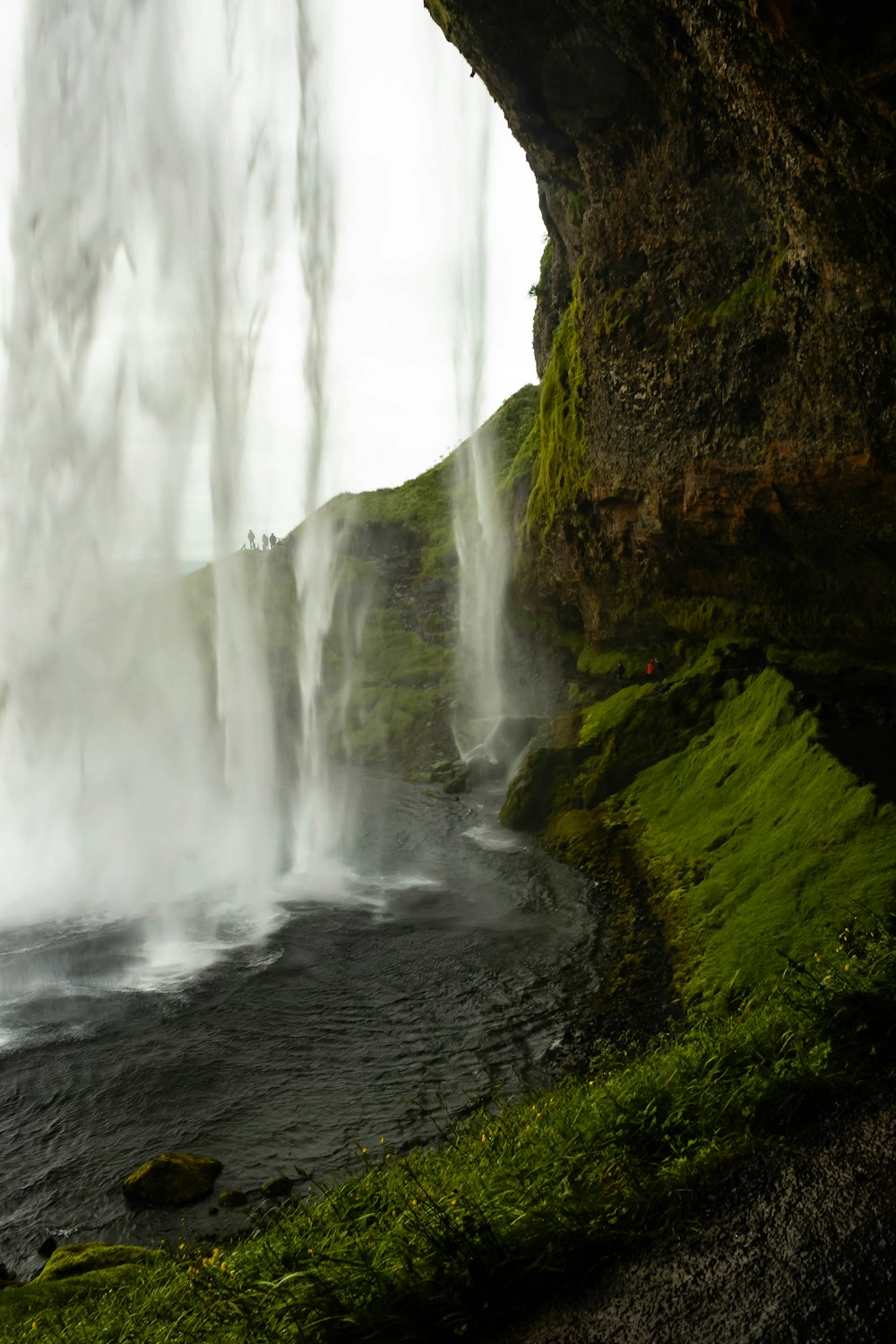 water falls on brown rocky mountain during daytime