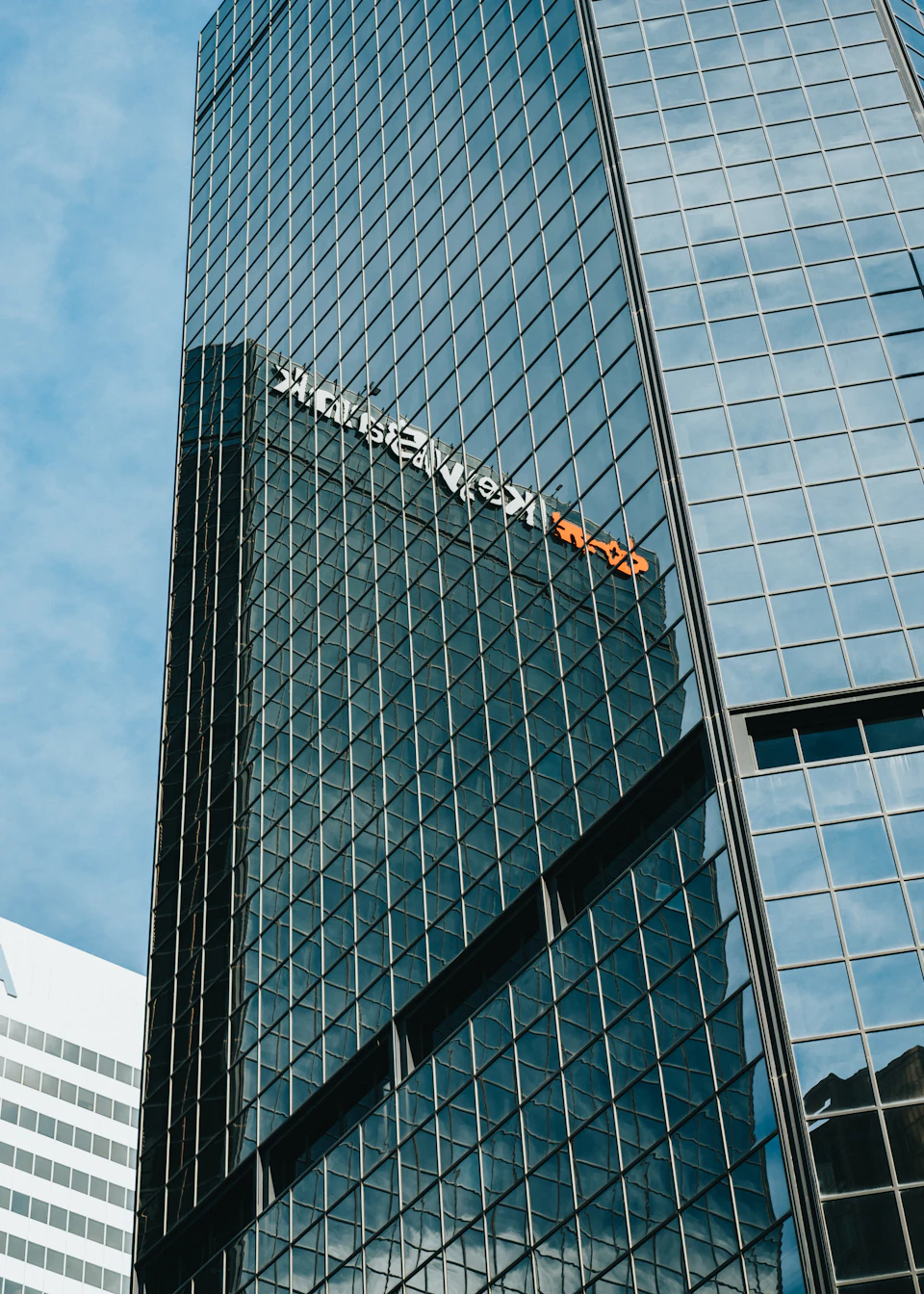 Tall modern glass building with triangular shape and reflective surface dominates city skyline