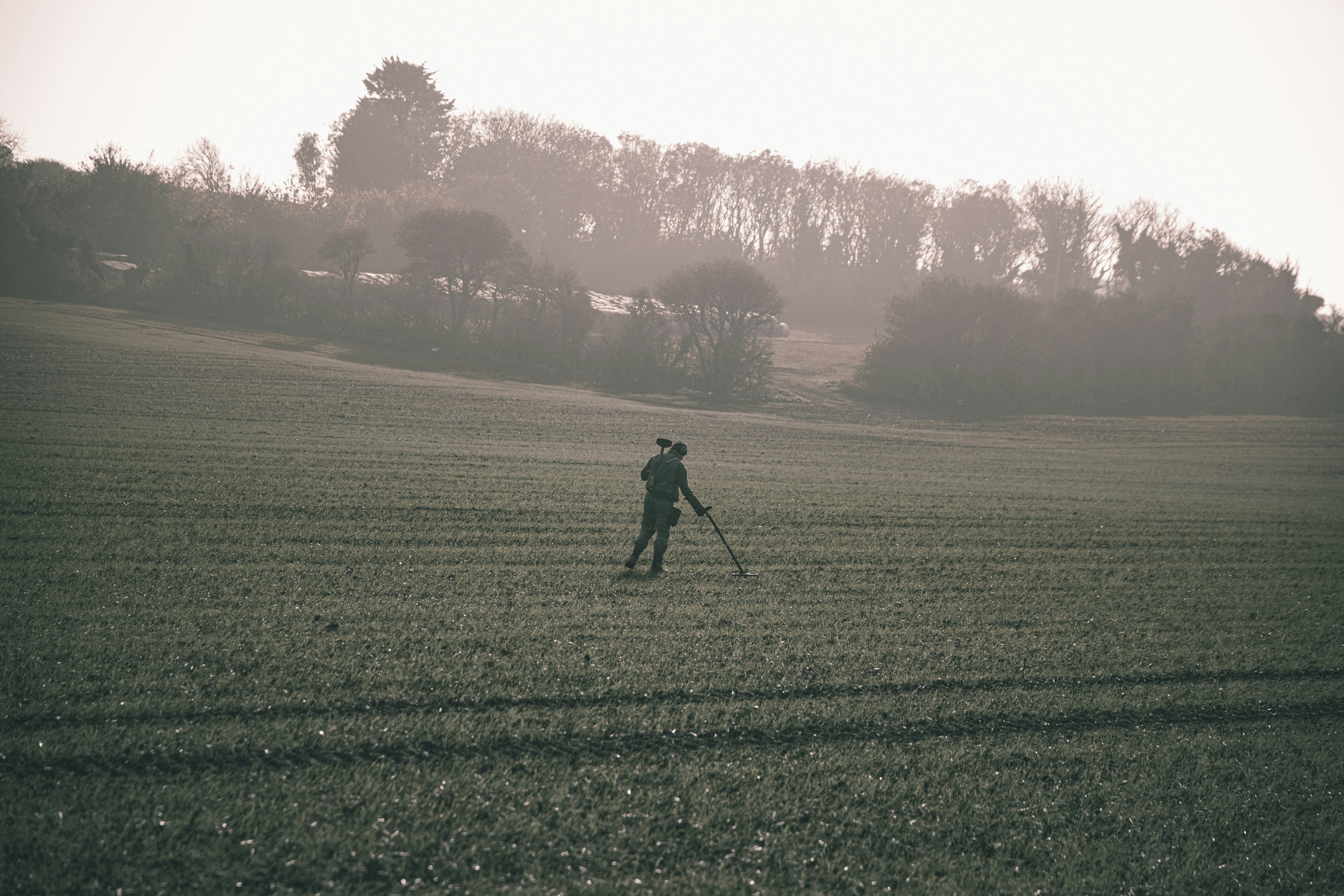 man in black jacket walking on green grass field during daytime