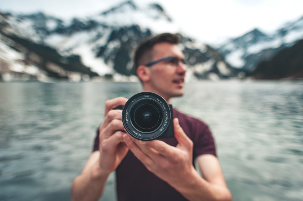 man in red crew neck t-shirt holding black camera