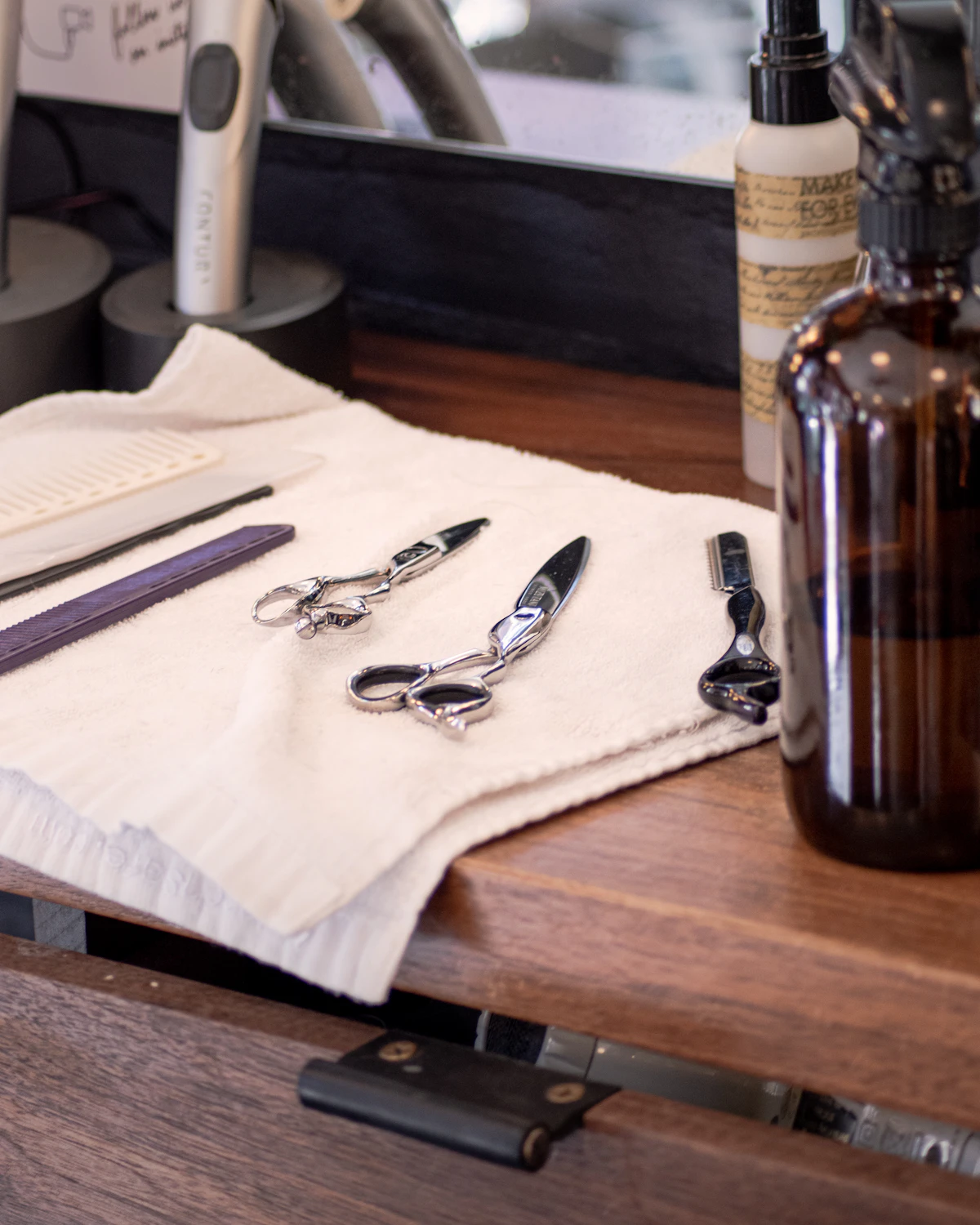 Ciseaux de coiffure posés sur un linge, à côté d'un flacon