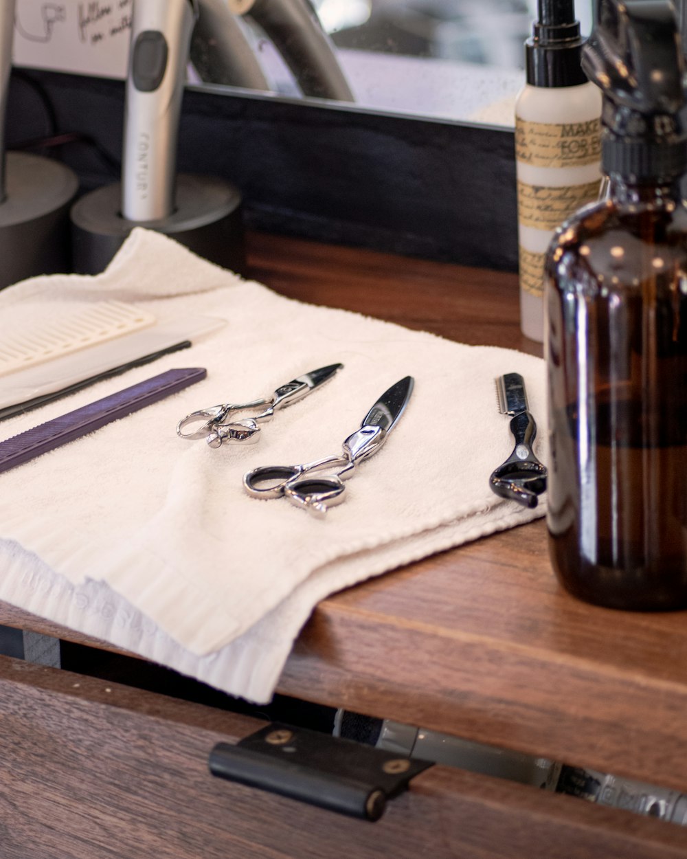 silver scissors beside brown glass bottle on brown wooden table