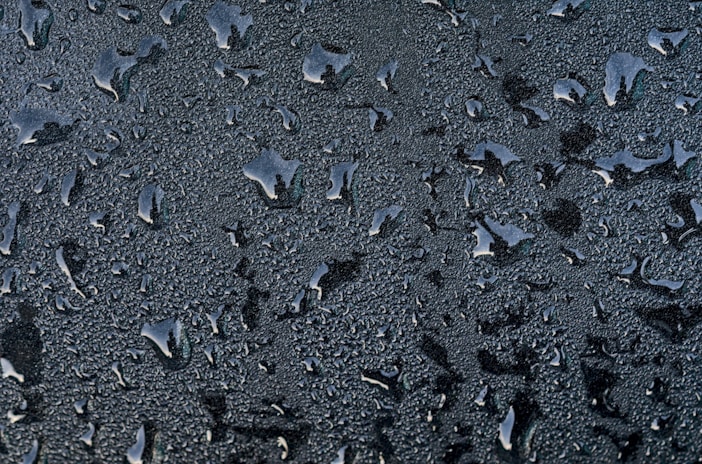 Water droplets beading on a treated surface, illustrating the rain-repelling barrier effect.