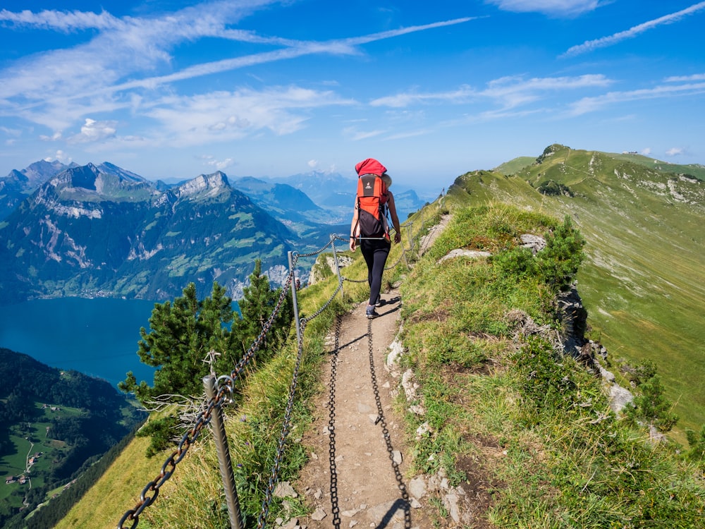 man in red jacket walking on pathway during daytime