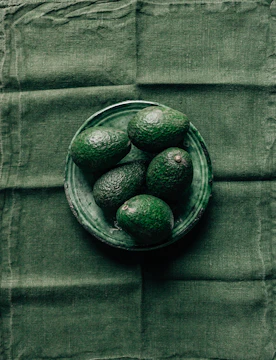 Close-up of ripe Haas avocados arranged on a deep navy cloth with rich gold accents.