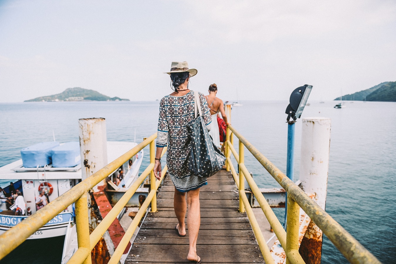 woman in black and white floral dress walking on wooden dock during daytime