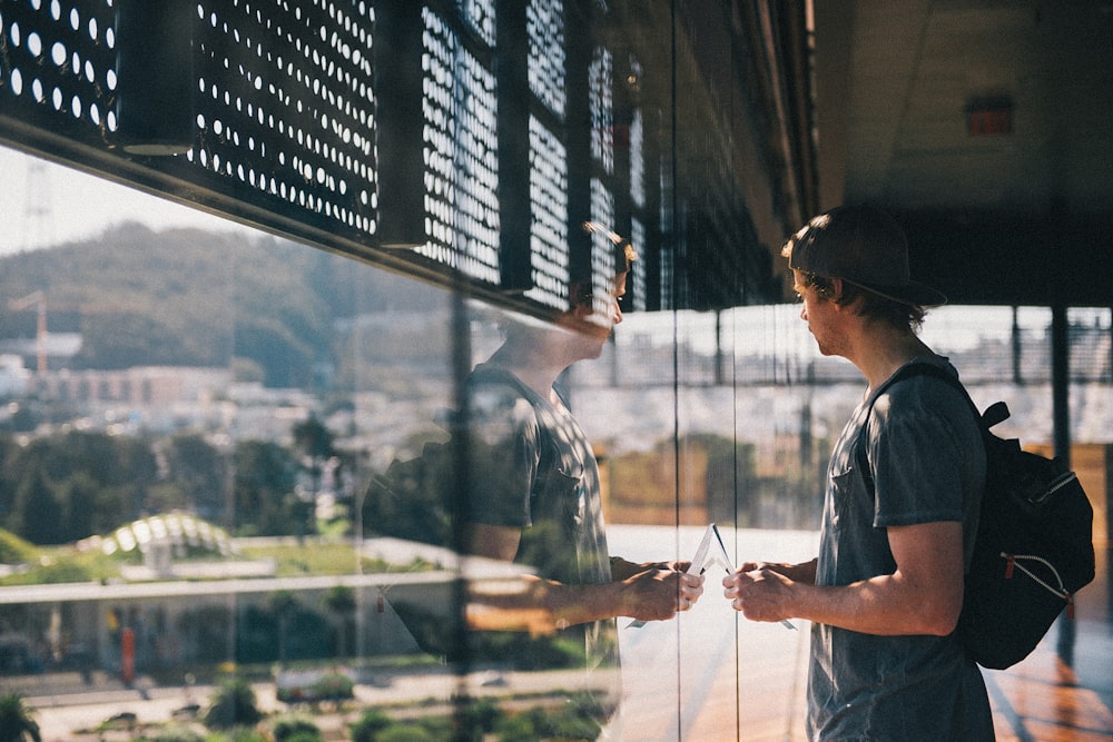 man in blue button up shirt standing near glass window