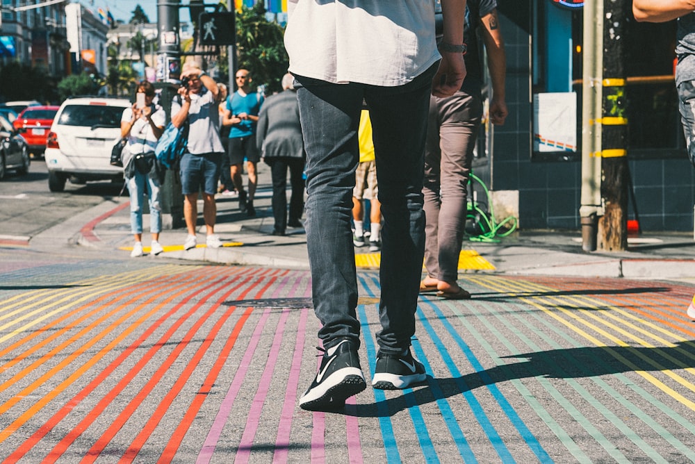 man in white shirt and black pants walking on sidewalk during daytime