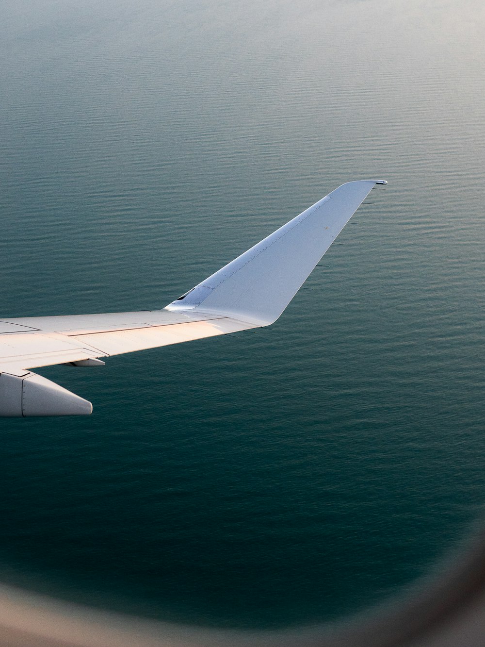 white airplane wing over blue sea during daytime
