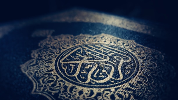 Intricate Arabic calligraphy and ornate patterns are embossed in gold on a dark background, creating a sense of elegance and reverence.