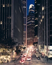 cars on road between high rise buildings during night time