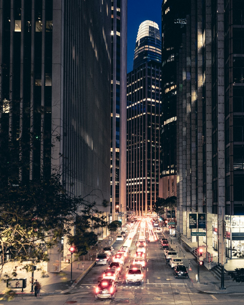 cars on road between high rise buildings during night time