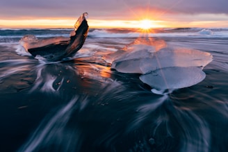 brown rock on body of water during sunset